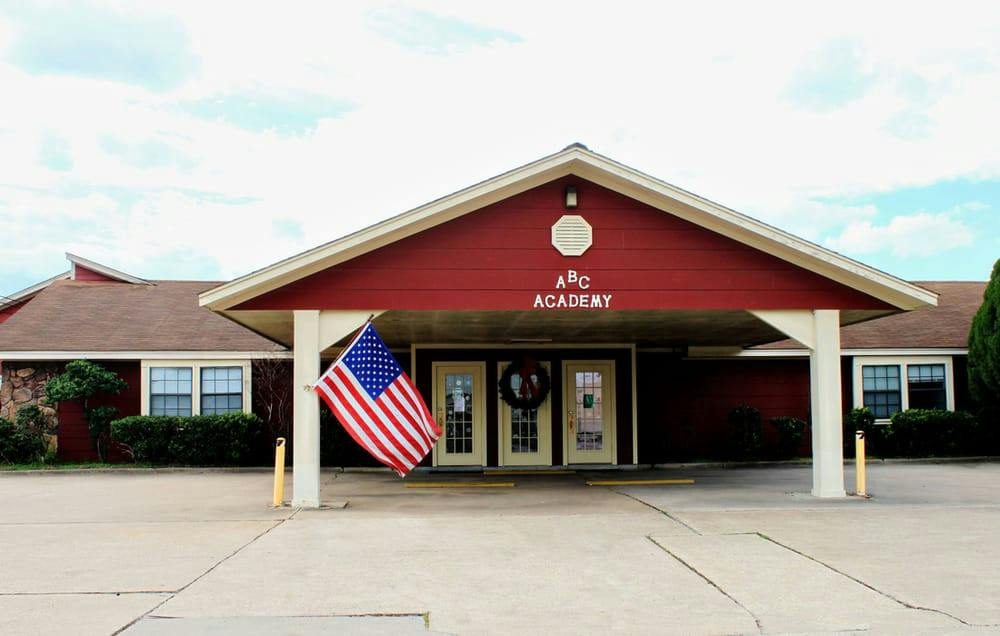 The red exterior and covered entrance of ABC Academy in Sugar Land