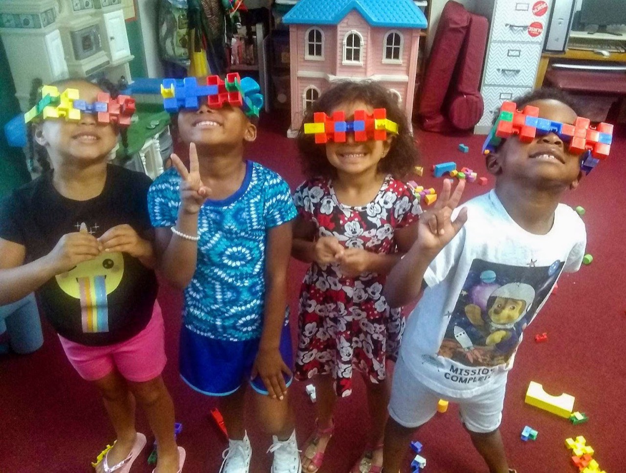 Four children smiling and showing off colorful creations made with building blocks