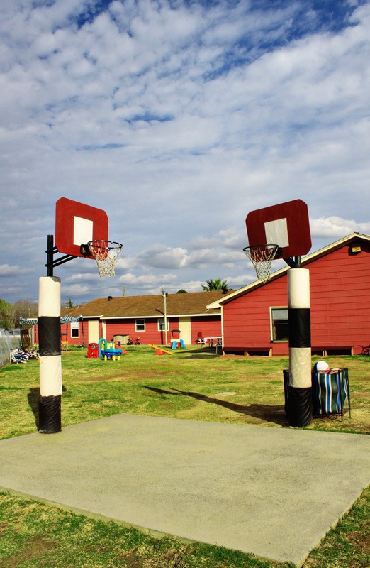 Outdoor basketball hoops beside the academy's grassy play space
